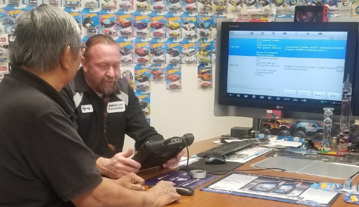 Jeffrey, owner of Limberlost Automotive, sitting at a table providing a customer with computer diagnostics of their vehicle
